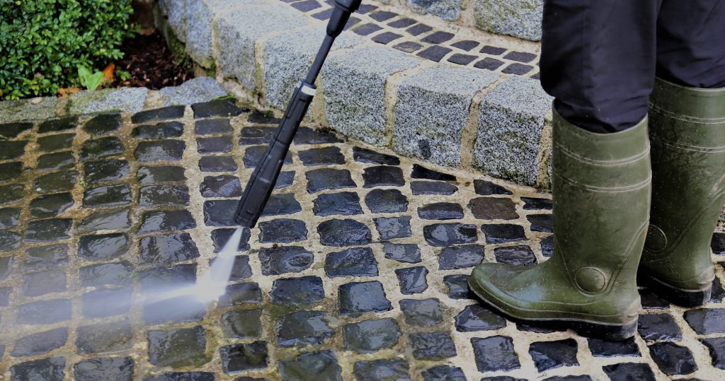 professional cleaning grout outside in green boots