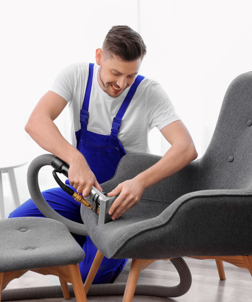 professional in blue suspenders cleaning chair upholstery